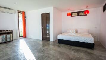 A modern bedroom with a large bed, a wooden bench, and a red pendant light.