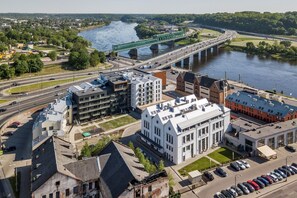 An aerial view of a cityscape with a prominent bridge, modern buildings, and a river. - King Mindaugas Apartments (Kaunas)