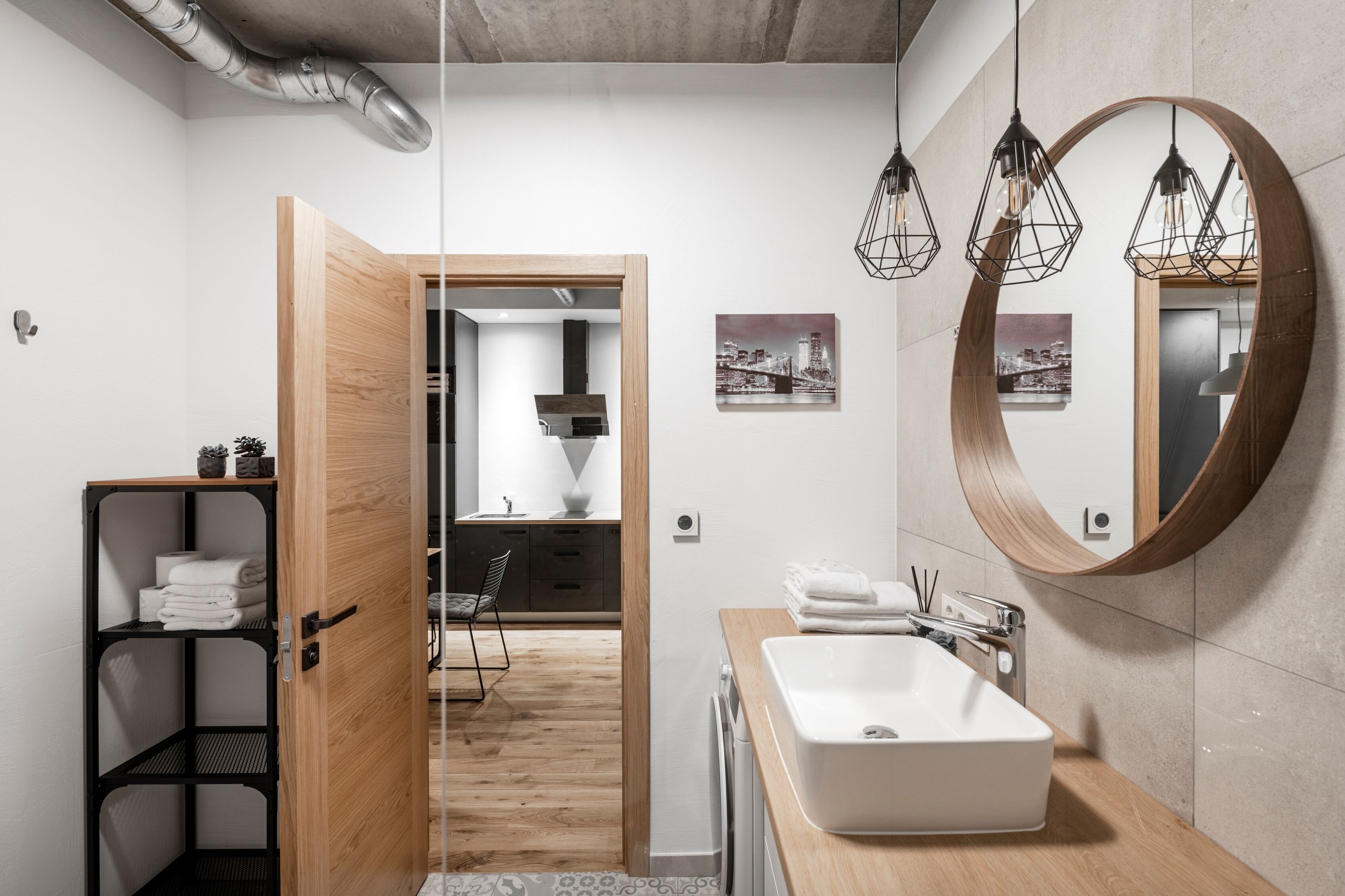 A modern bathroom with a wooden vanity, a large mirror, and a white sink.