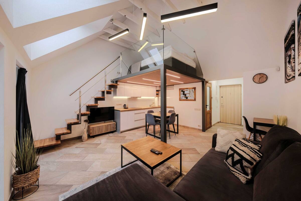 A modern loft apartment with a kitchen, dining area, and living room.