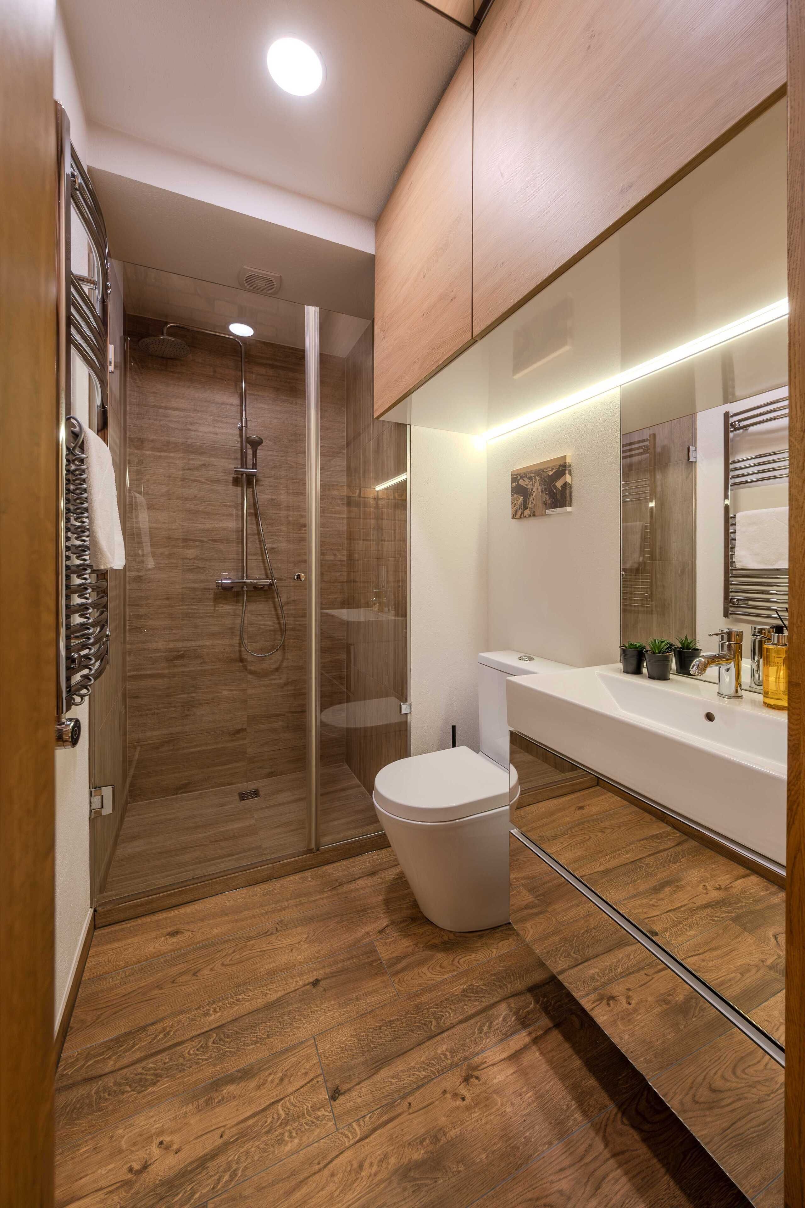Een moderne badkamer met een douchecabine van glas, een wit toilet en een wastafel met spiegel.