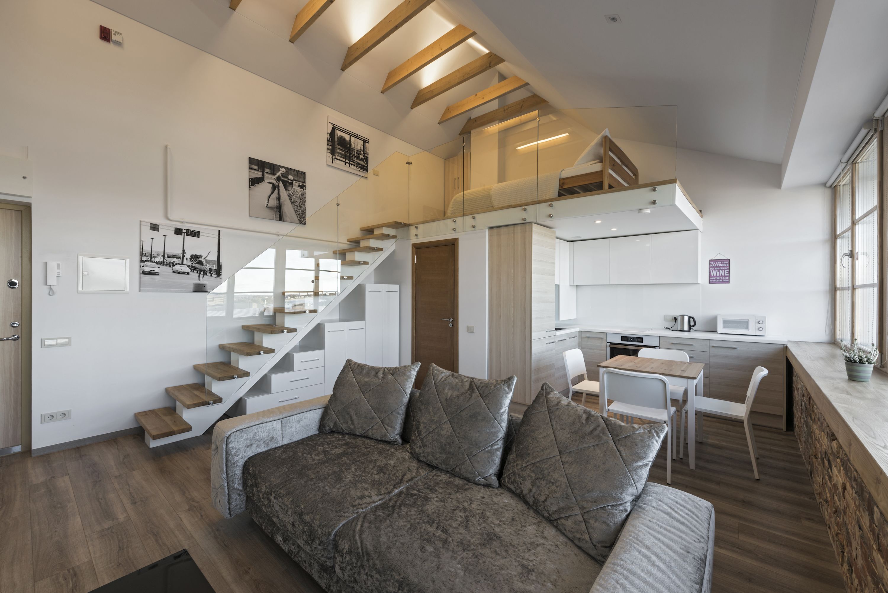Una sala de estar moderna con un sofá, una escalera, una cocina y un comedor.