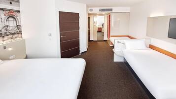 A hotel room with two beds, a wardrobe, a TV, and a bathroom visible through an open door.