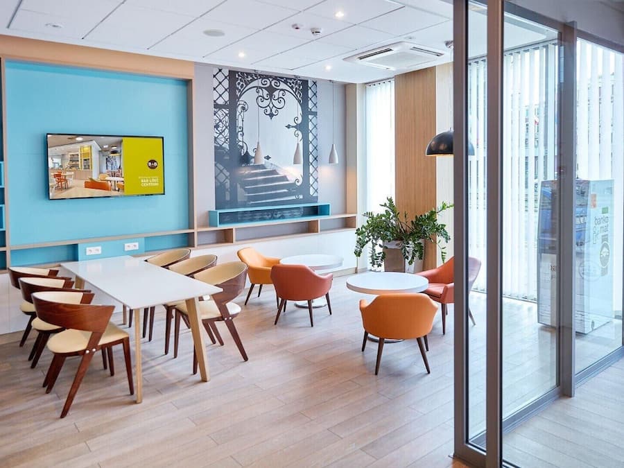 A modern interior with a blue accent wall, a large mural, and a seating area with tables and chairs.