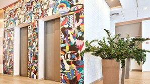 A lobby with colorful abstract wall art, a potted plant, and two elevators. - B&B Hotel Łódź Centrum (Lodz)