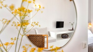 A modern bedroom with a white bed, a mounted TV, and a white console table. - Anemomylos Residence (Paros)