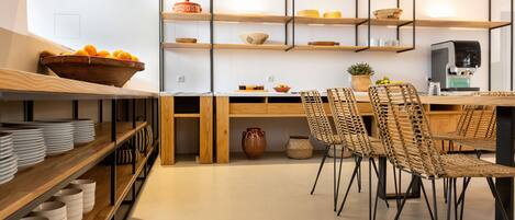 A modern kitchen with wooden shelves, a dining table with chairs, and a coffee machine.