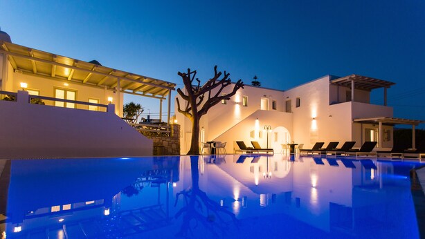 A modern hotel with a swimming pool, lounge chairs, and a covered outdoor area. - Anemomylos Residence (Paros)
