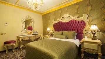 Una lujosa habitación de hotel con una cama grande, un cabecero decorado, un espejo y dos mesitas de noche con lámparas.