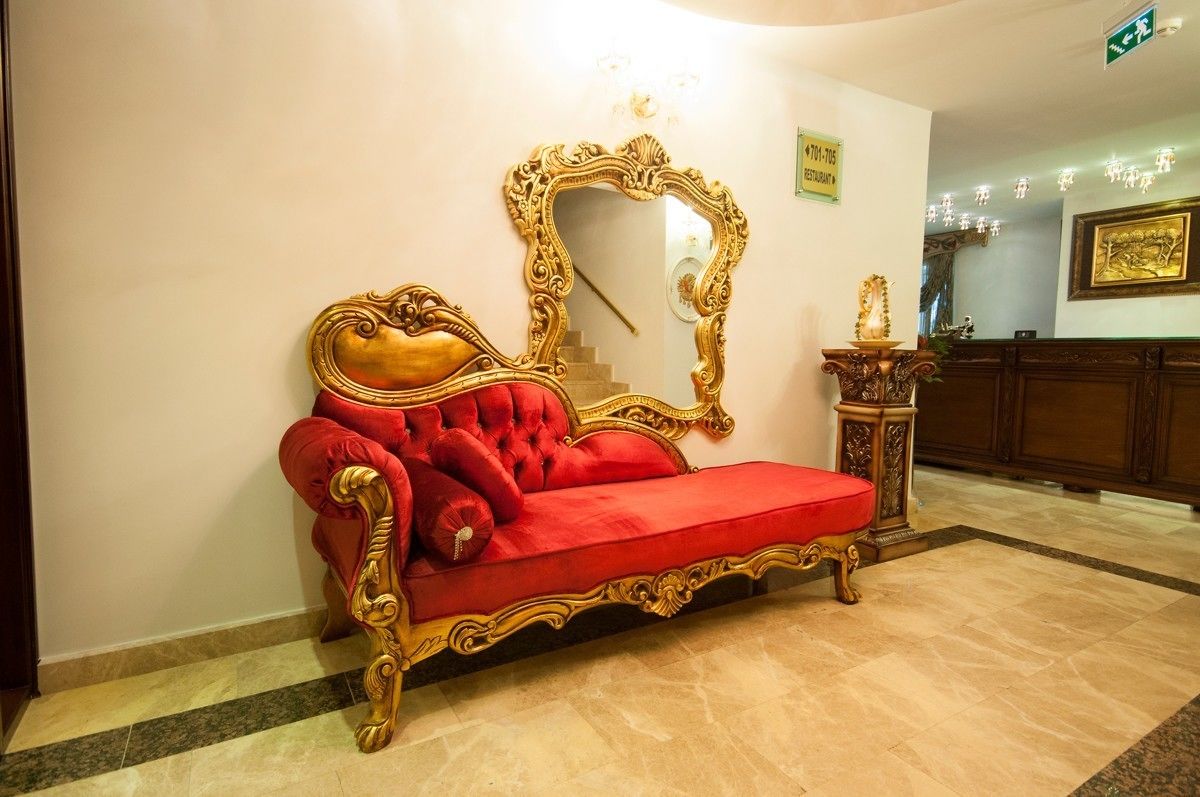 A red sofa with gold detailing in a lobby area.