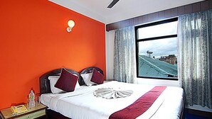 Ein Hotelzimmer mit einem großen Bett, einem Nachttisch mit Telefon und einem Fenster mit Blick auf ein Gebäude.