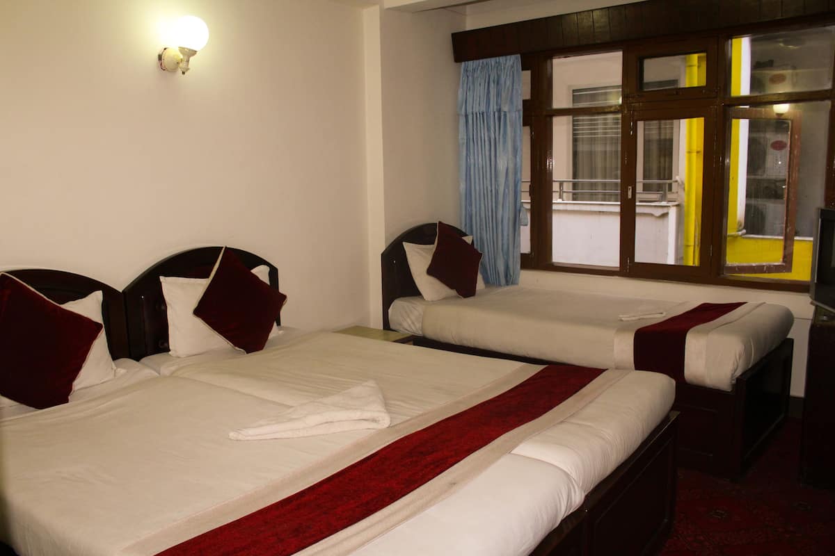 Two single beds with red and white bedding, a white towel, and a window with curtains.