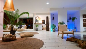 A spacious lobby with a modern design, featuring a large wooden chair, a glass coffee table, and several potted plants. - Le Battant Des Lames (Saint-Pierre)