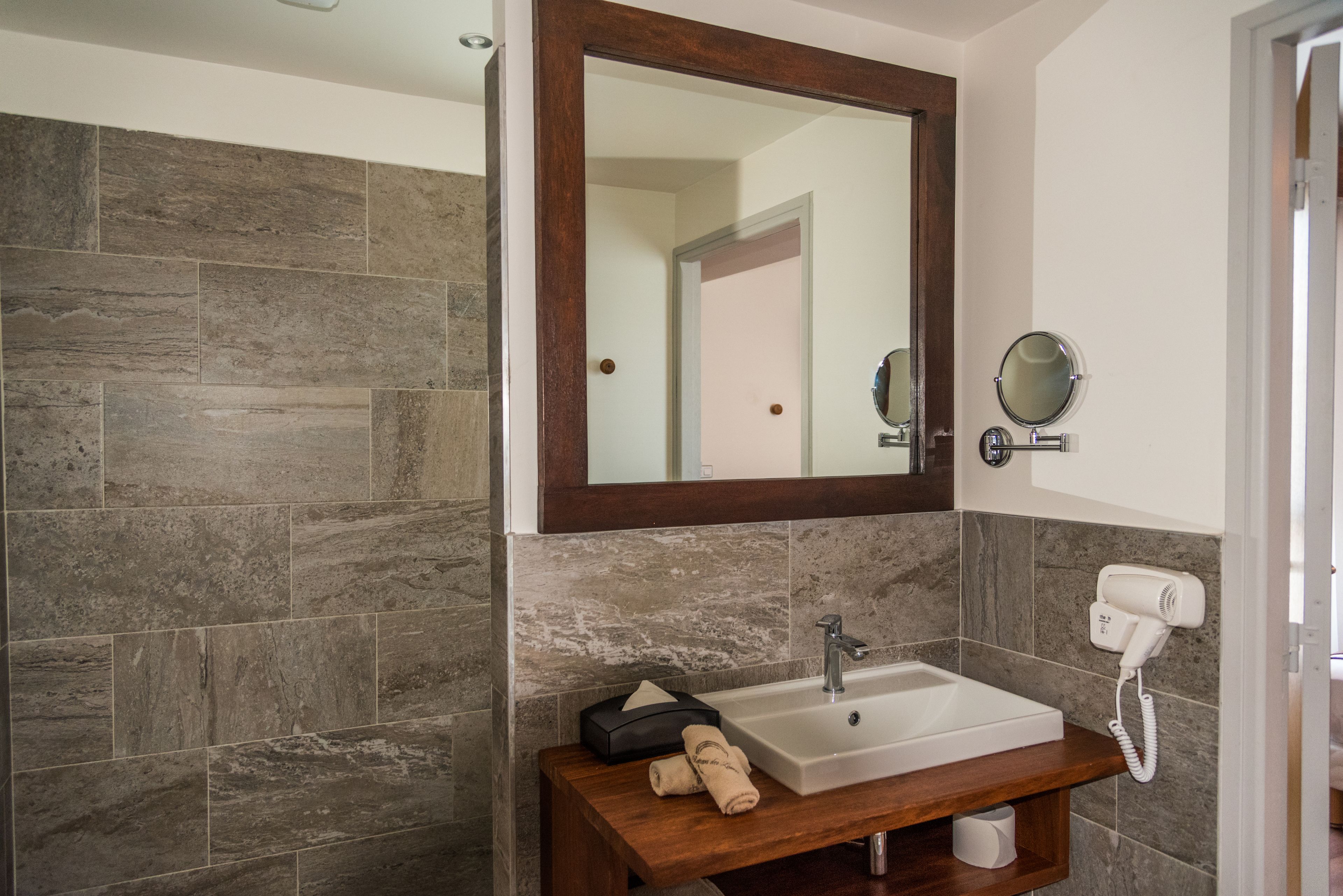Un baño con un espejo grande, un lavabo, un secador de pelo y una toalla en la encimera.