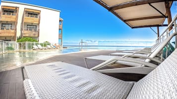 Una piscina al aire libre, sillones reclinables de piscina