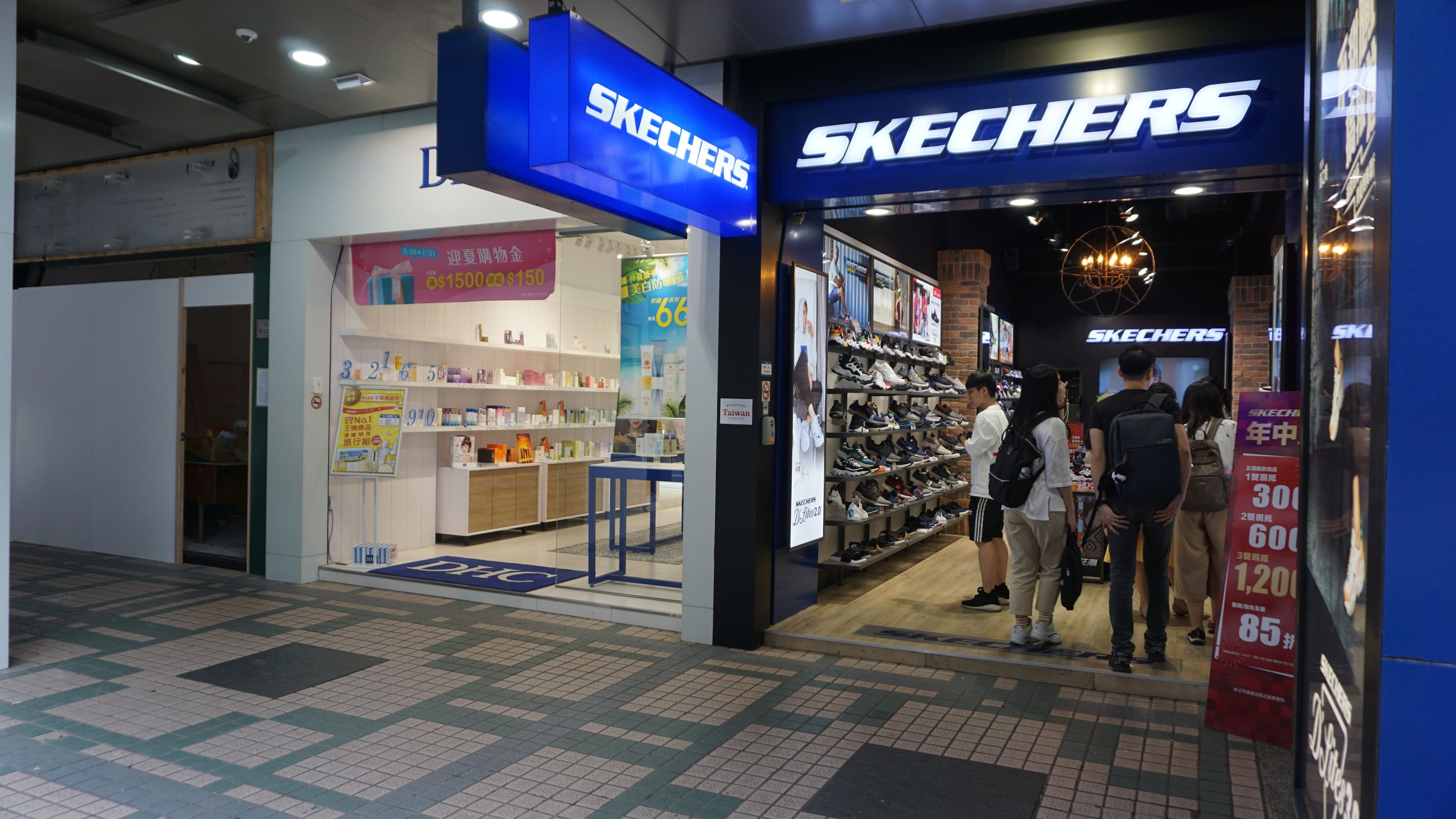 A Skechers store with a blue sign, shelves with shoes, and a display of various products.