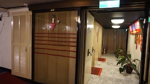 Een hotelentree met een houten deur, een brandblusser en een bloempot met plant.