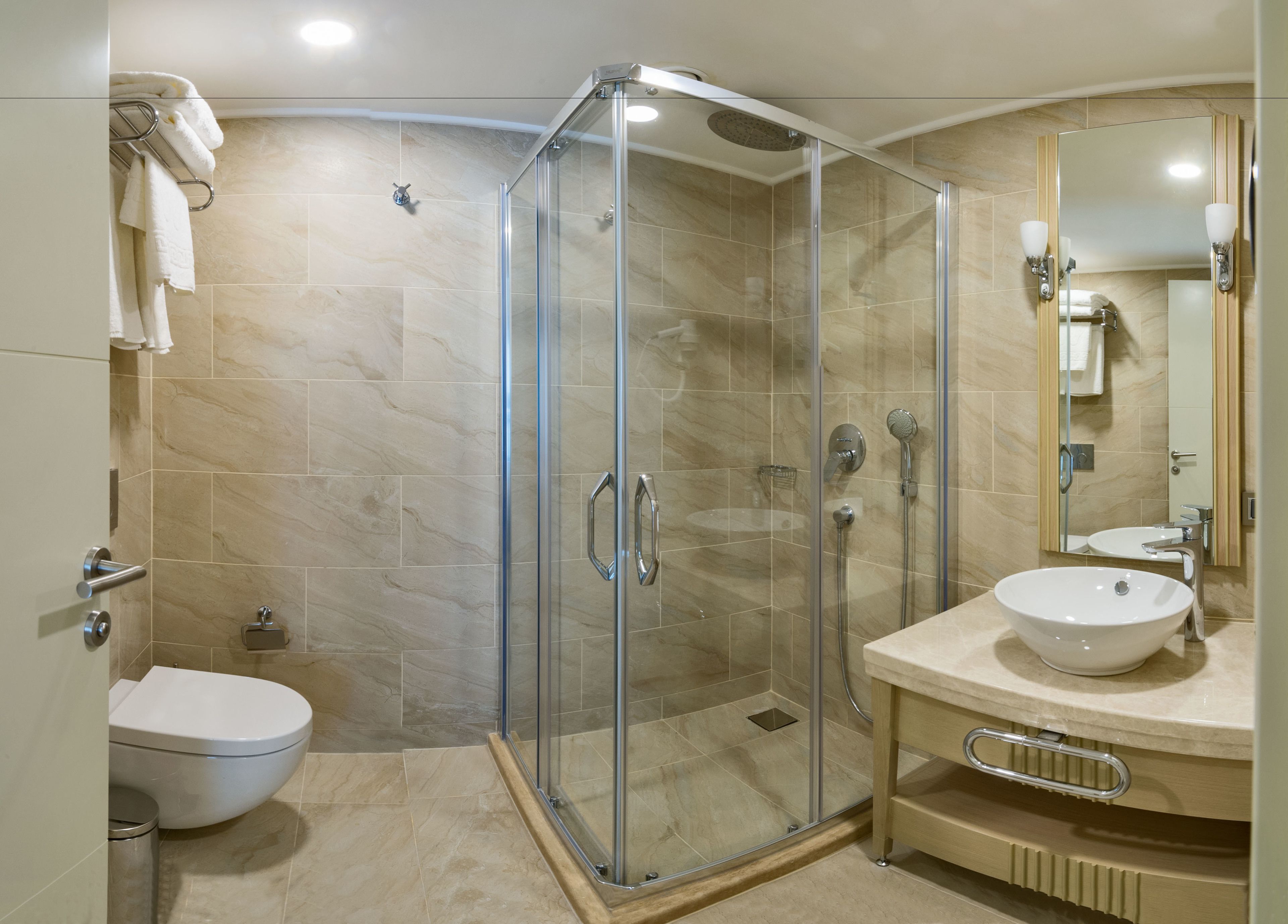 A modern bathroom with a glass-enclosed shower, a white sink, and a toilet.
