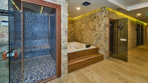 Un baño moderno con ducha envuelta en cristal, bañera independiente y paredes de piedra.
