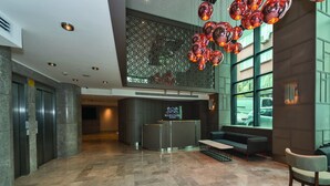 Un vestíbulo de hotel con mostrador de recepción, zona de estar y techo decorativo.