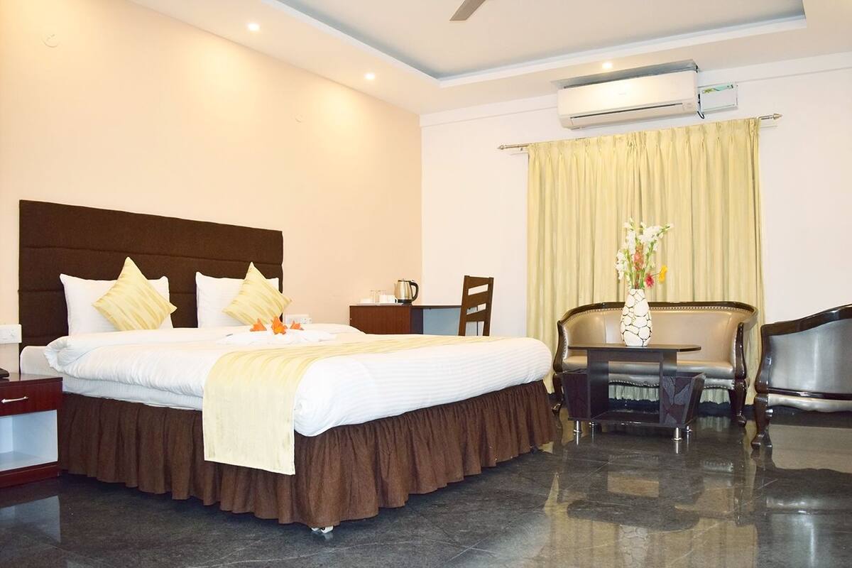 Een hotelkamer met een groot bed, een bureau, een stoel en een airconditioning.
