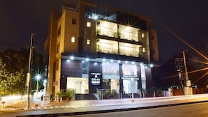 Ein mehrstöckiges Hotel mit moderner Fassade, beleuchtetem Eingang und Schildern, die einen Spa-Bereich und ein Experience Center anzeigen.