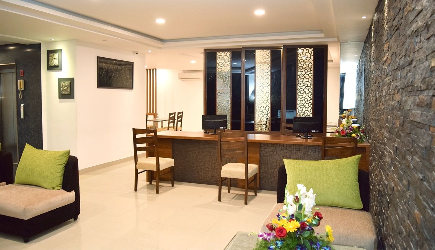 A modern hotel lobby with a reception desk, seating area, and a decorative wall.