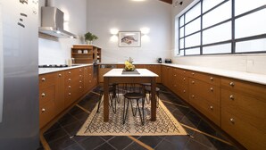A modern kitchen with wooden cabinets, a white countertop, and a large window. - Villa Meliti (Athens)