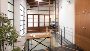 A staircase with a wooden railing, a table with decorative items, and a cabinet. - Villa Meliti (Athens)