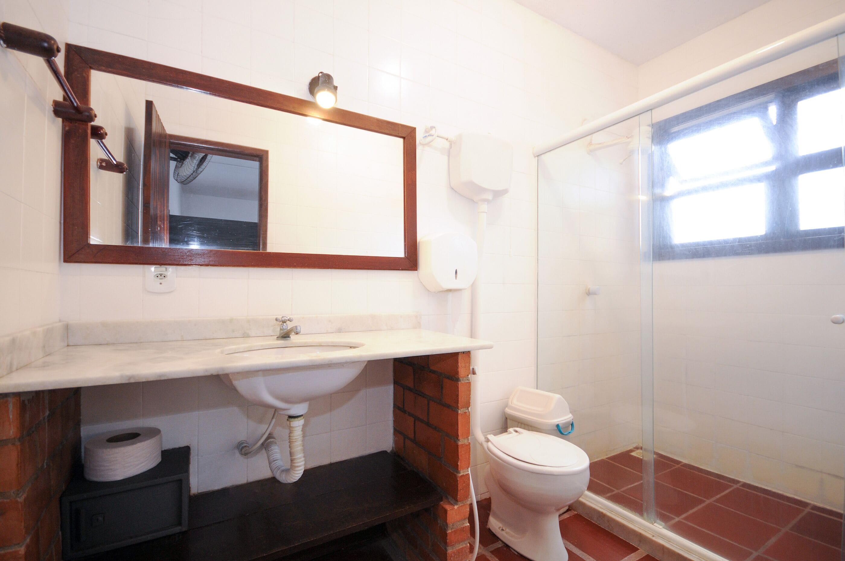 Une salle de bain équipée d’un lavabo, d’un miroir, de toilettes et d’une douche à parois en verre.