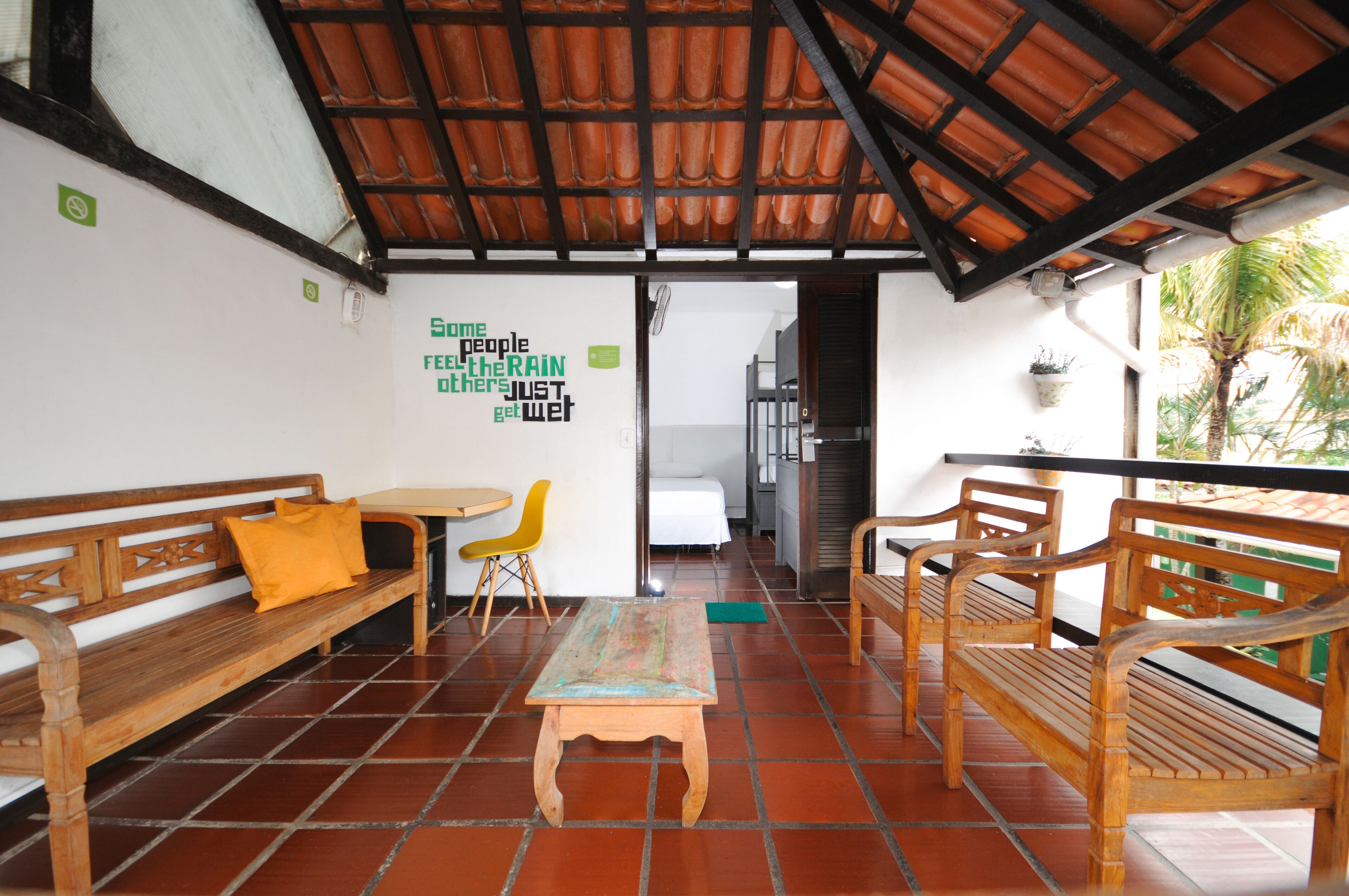 Una habitación con bancos de madera, una pequeña mesa y una pared con un cartel verde.