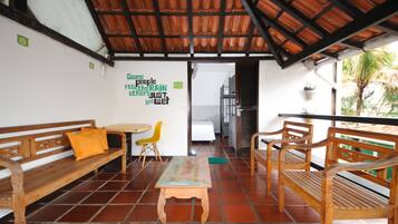 Una habitación con bancos de madera, una pequeña mesa y una pared con un cartel verde.