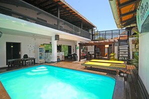 Zona de piscina con área de descanso cubierta y un bar.