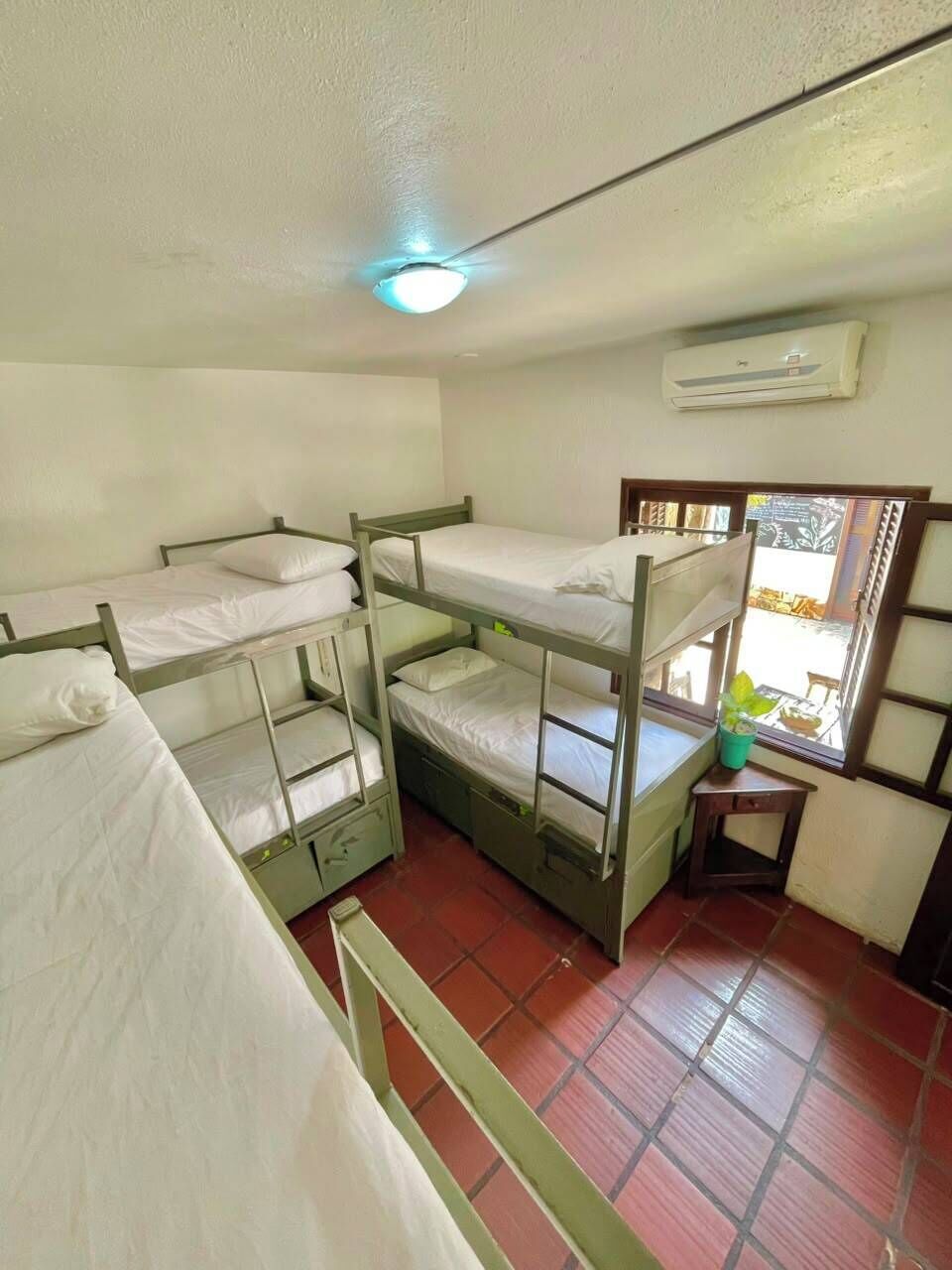 Un dormitorio con literas, una ventana con vistas, un equipo de aire acondicionado y un ventilador de techo.