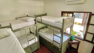 Un dormitorio con literas, una ventana con vistas, un equipo de aire acondicionado y un ventilador de techo.