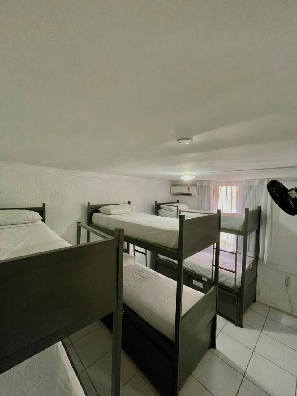 Un dormitorio con literas, ventilador de techo y ventana con cortinas.