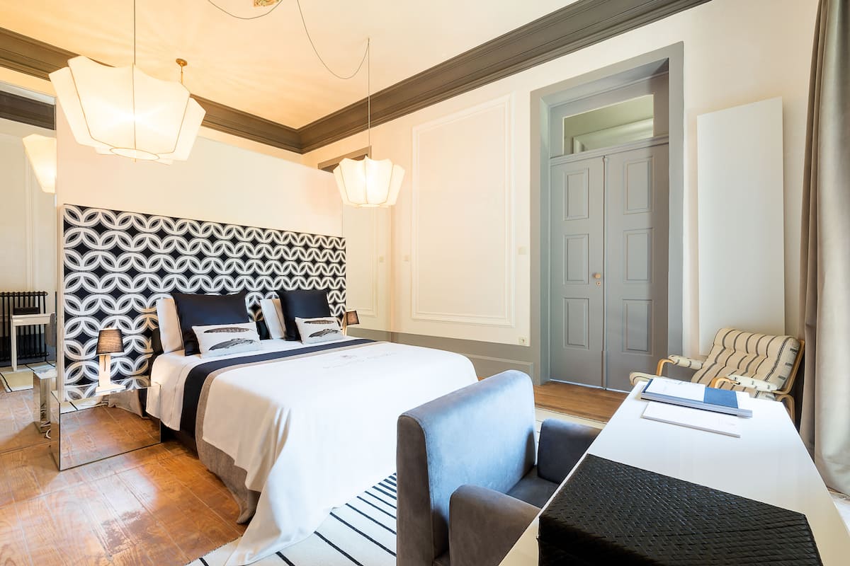 A modern hotel room with a large bed, a desk, and a chair.