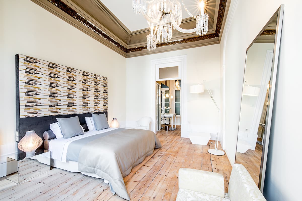 A modern bedroom with a large bed, a chandelier, and a mirror.