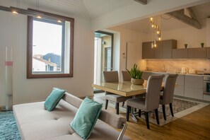 Una sala moderna con una mesa de comedor de vidrio, un sofá color beige y cojines color turquesa.