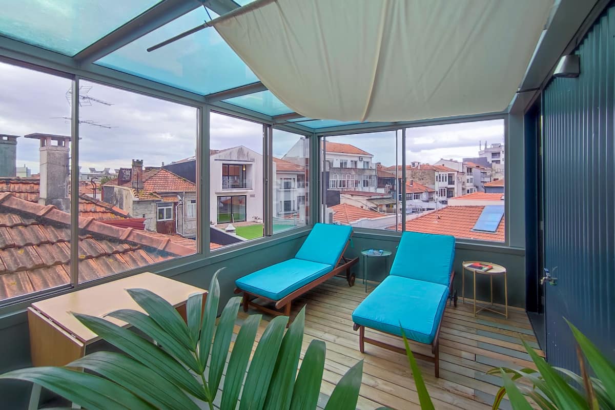 A sunroom with large windows, a wooden floor, and a blue sofa.