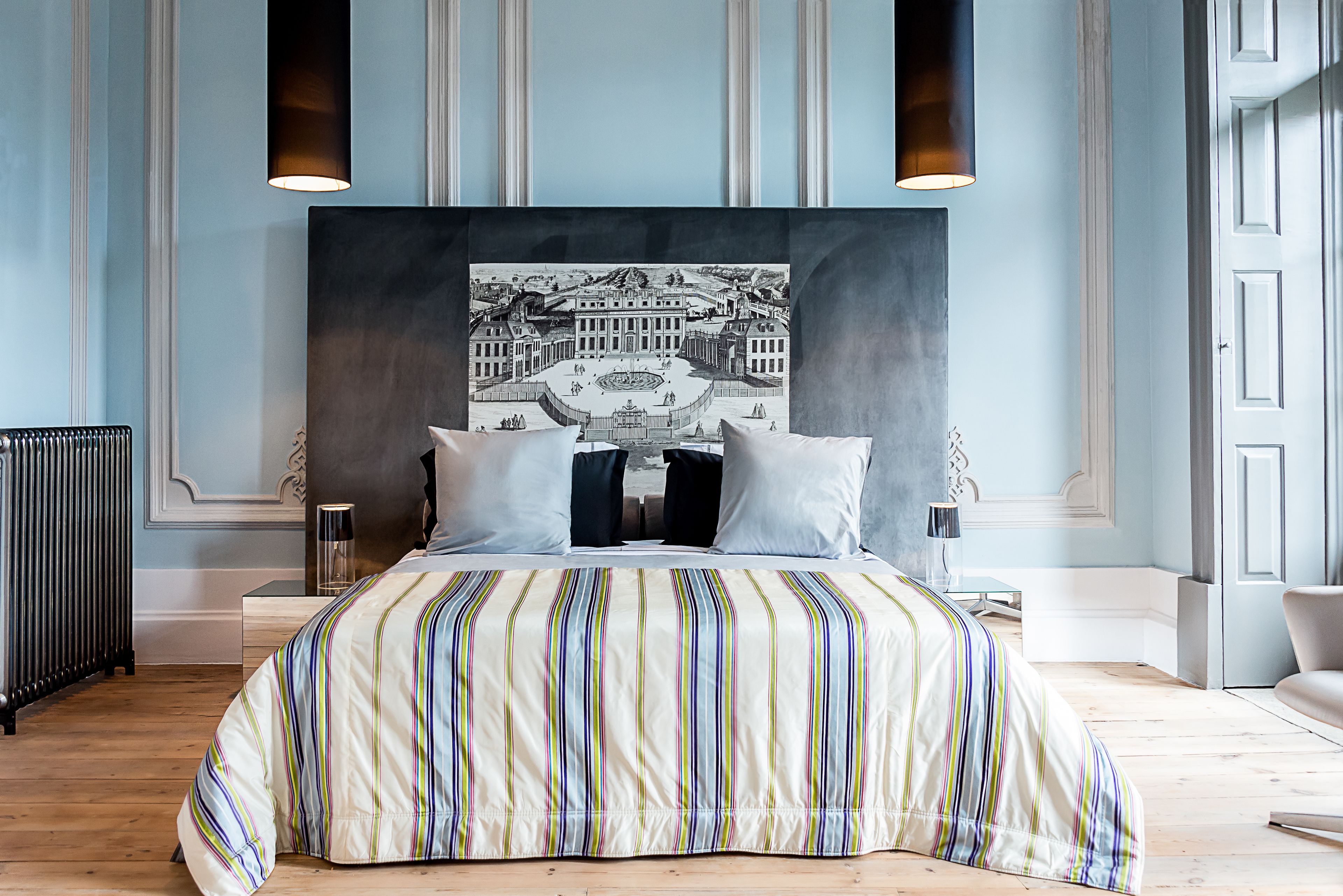 A bedroom with a large bed, a black and white artwork above the bed, and a modern lamp beside the bed.