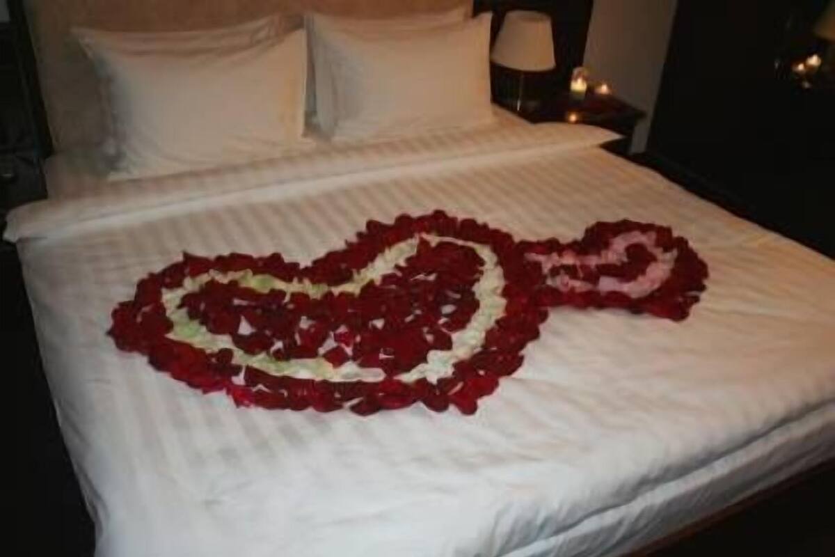 A bed with a heart-shaped arrangement of red and white flowers.