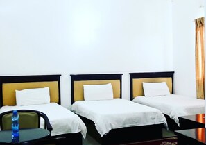 A hotel room with three single beds, a small table with a chair, and a bottle of water on the table. - Hotel Al-Khalil Machava (Matola)