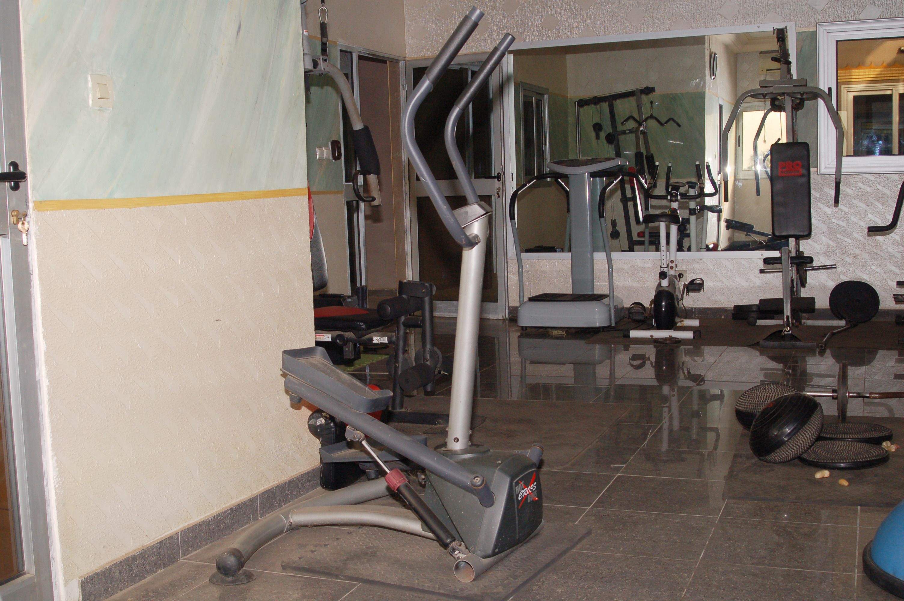 A gym with exercise equipment, including a treadmill, elliptical, and weights.