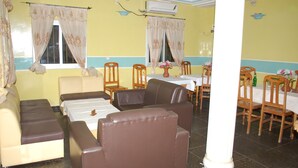 Habitación de hotel con sofá, sillas, una mesa de comedor y un pilar.