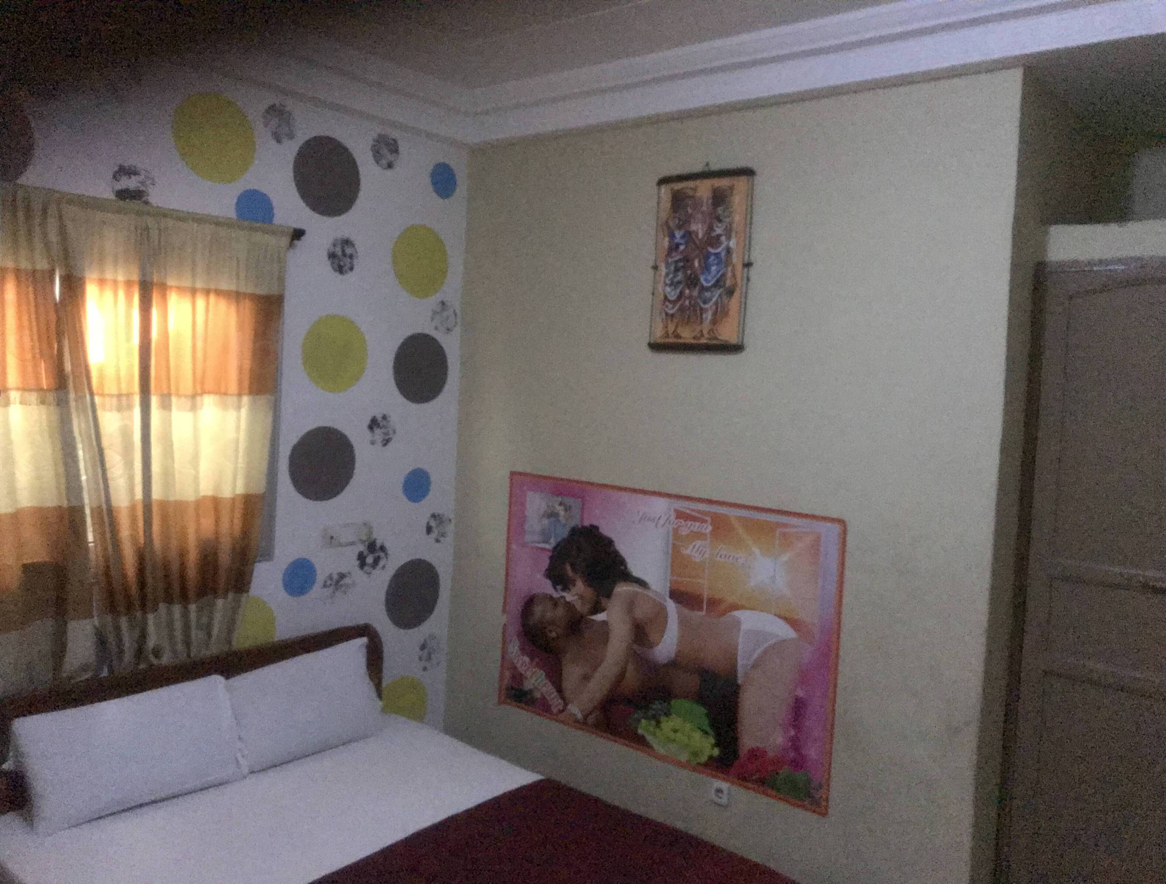 A bedroom with a bed, a polka dot wall, a framed picture, and a door.