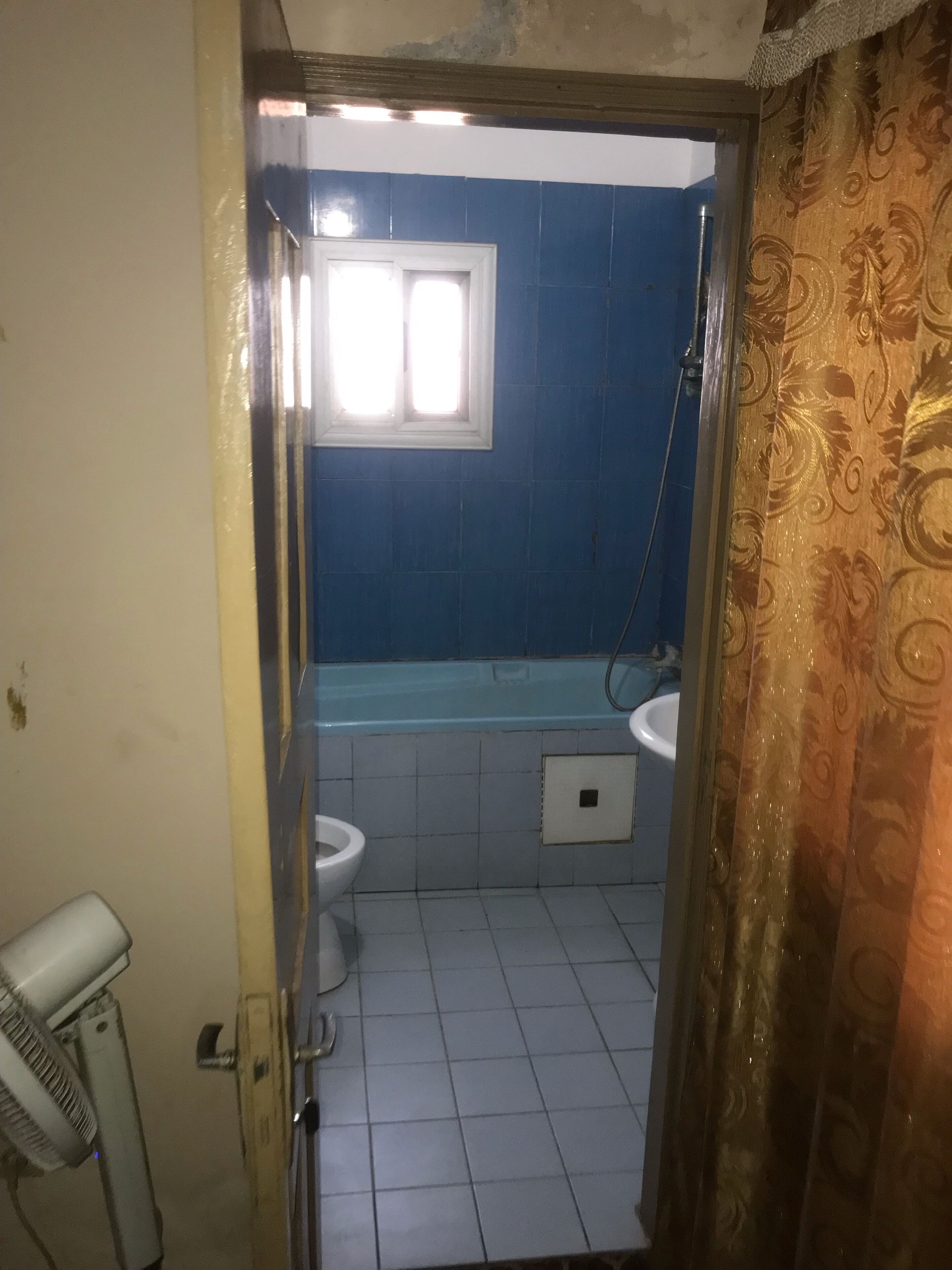 Een badkamer met een badkuip, twee toiletten en een raam.
