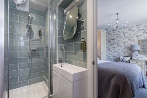 Un baño con cabina de ducha de vidrio, un lavabo blanco y un espejo.