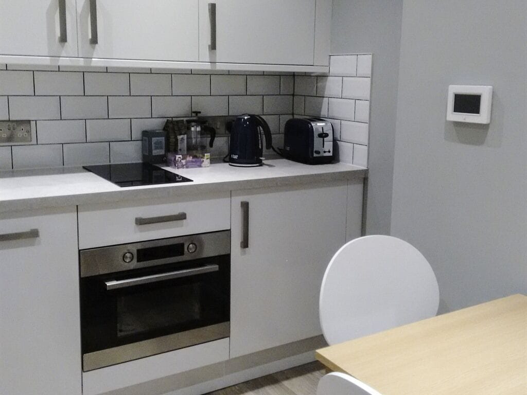 A kitchen with white cabinets, a black stove, a coffee maker, and a toaster.