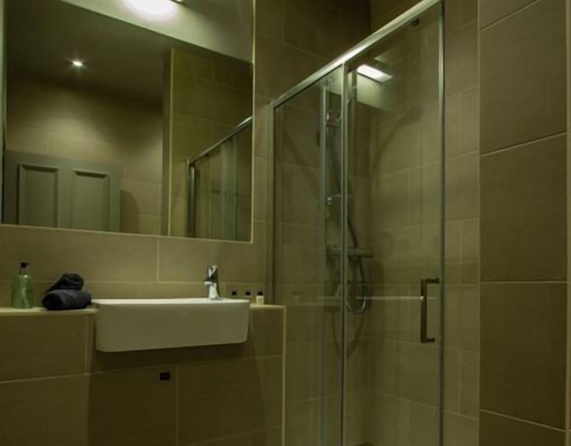 A modern bathroom with a glass-enclosed shower, a sink with a towel, and a mirror.